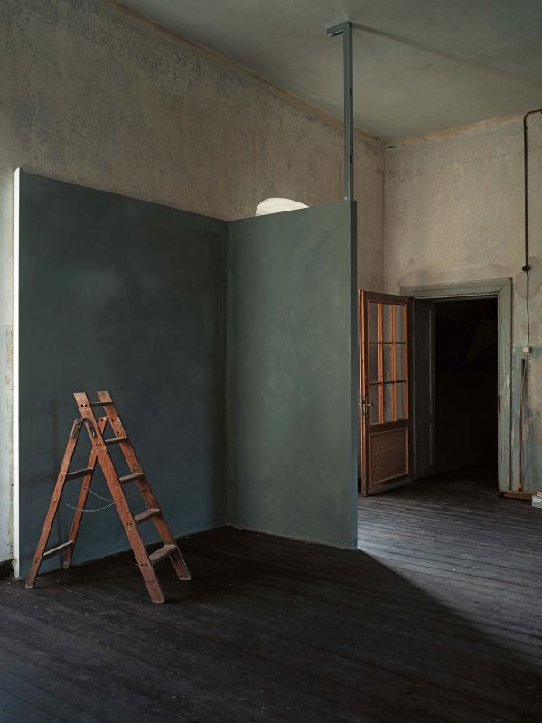 Ein Raum mit einer Holztür, in dem eine Leiter an einer gestrichenen Wand steht