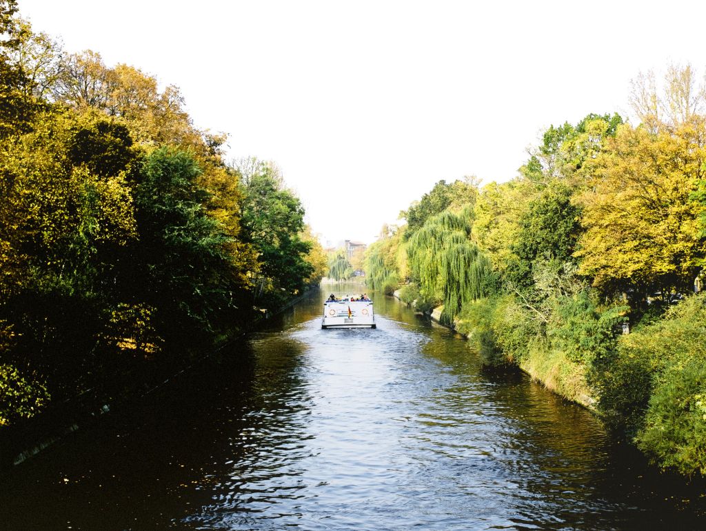 Eine Fähre fährt auf einem Berline Kanal zwischen Uferböschungen